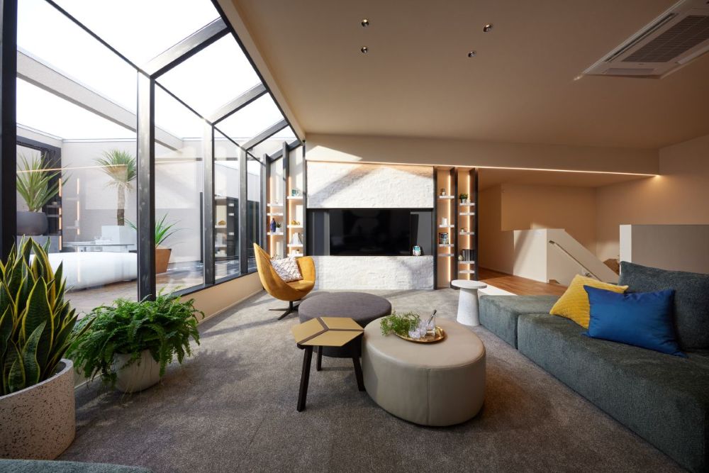 シエルホームデザインのモデルハウス。リビングのテレビ背面には天然石のアクセントウォールを採用し、中庭へと続く大開口サッシが開放感を演出。