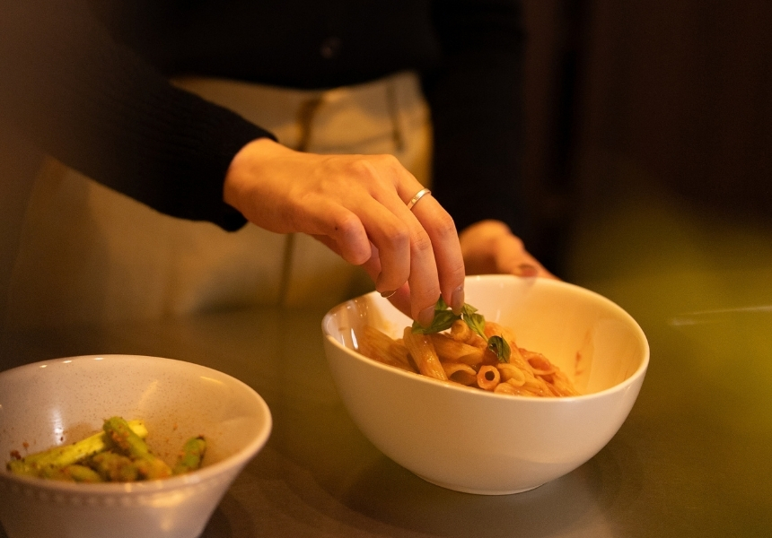 米沢市の完成邸見学会・キッチンで盛り付けたパスタにバジルを添える手元・家族の食事づくりの暮らしイメージ
